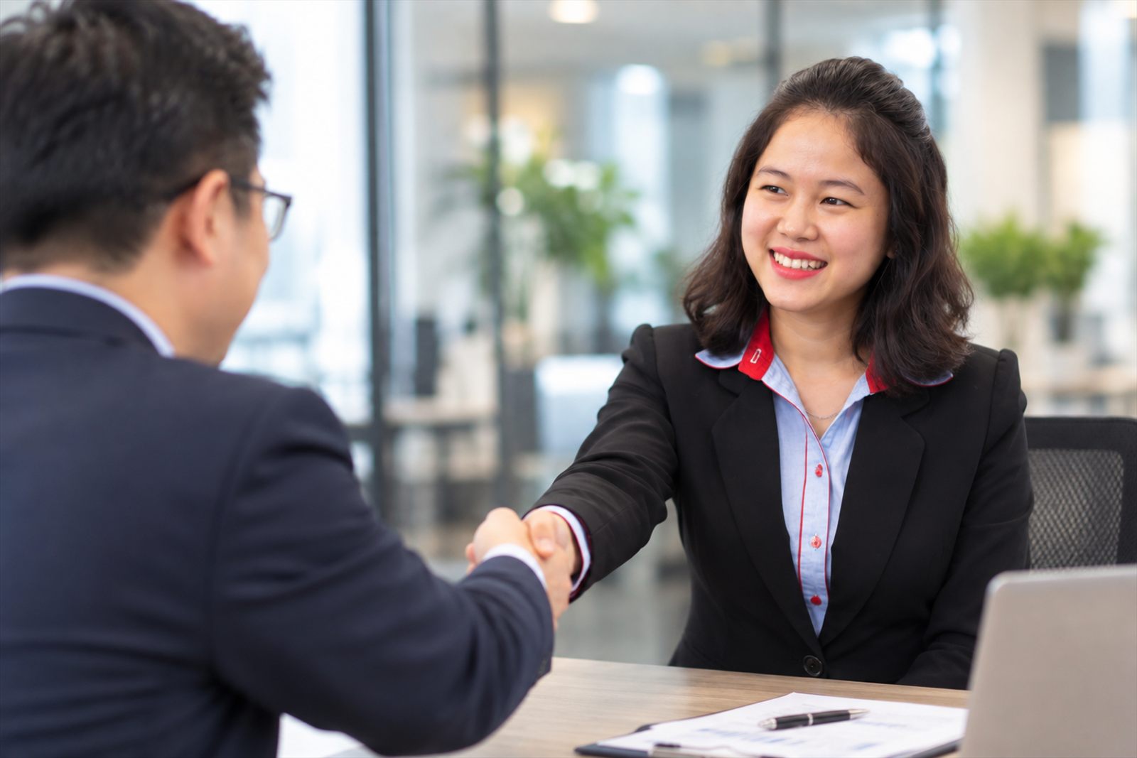 An IGS Consulting adviser shaking hands with a new client across a meeting table