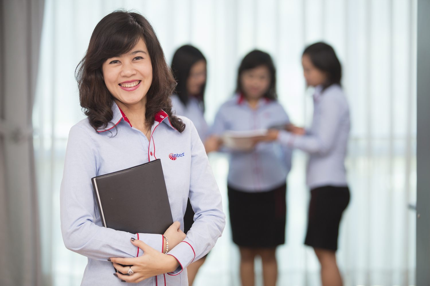An IGS Consulting corporate secretary holding a client file, colleagues working behind